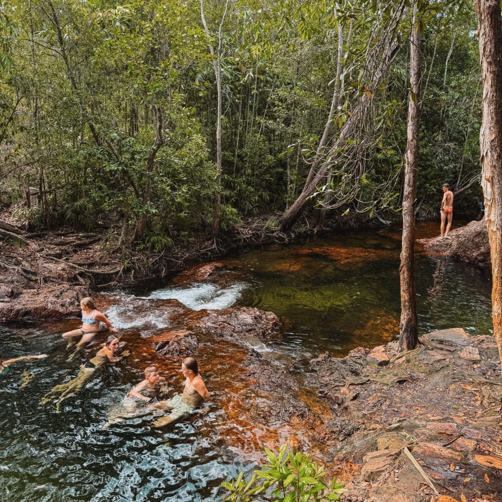 People in a water hole within a forest - day trips from Darwin