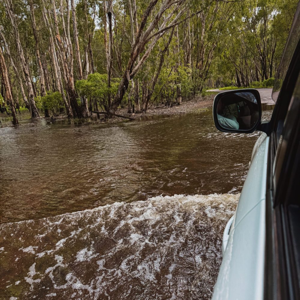 A car driving through a flooded road through a forest - day trips from Darwin