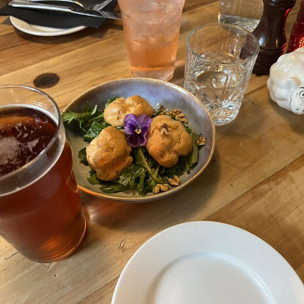 Three puffs in a bowl next to a glass of a red drink at a restaurant near Milford Sound