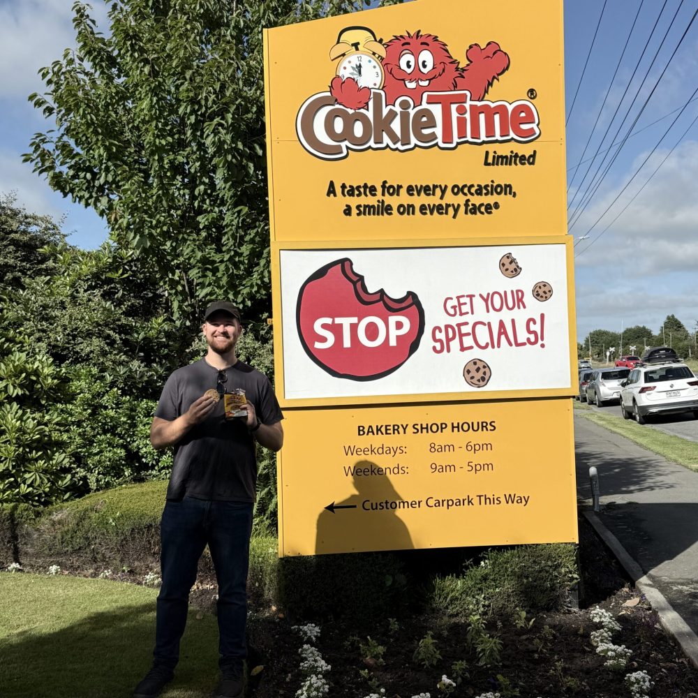 New Zealand-Mount Cook-Christchurch-Dunedin-2 A man standing in front of a sign on a trip from Christchurch to Dunedin
