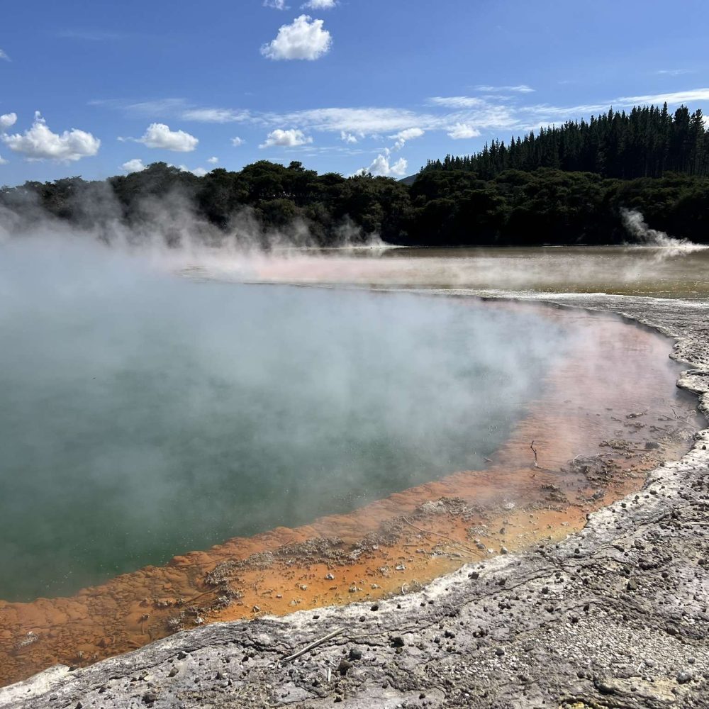 A teal and orange geothermal pool in a park near Rotorua, New Zealand