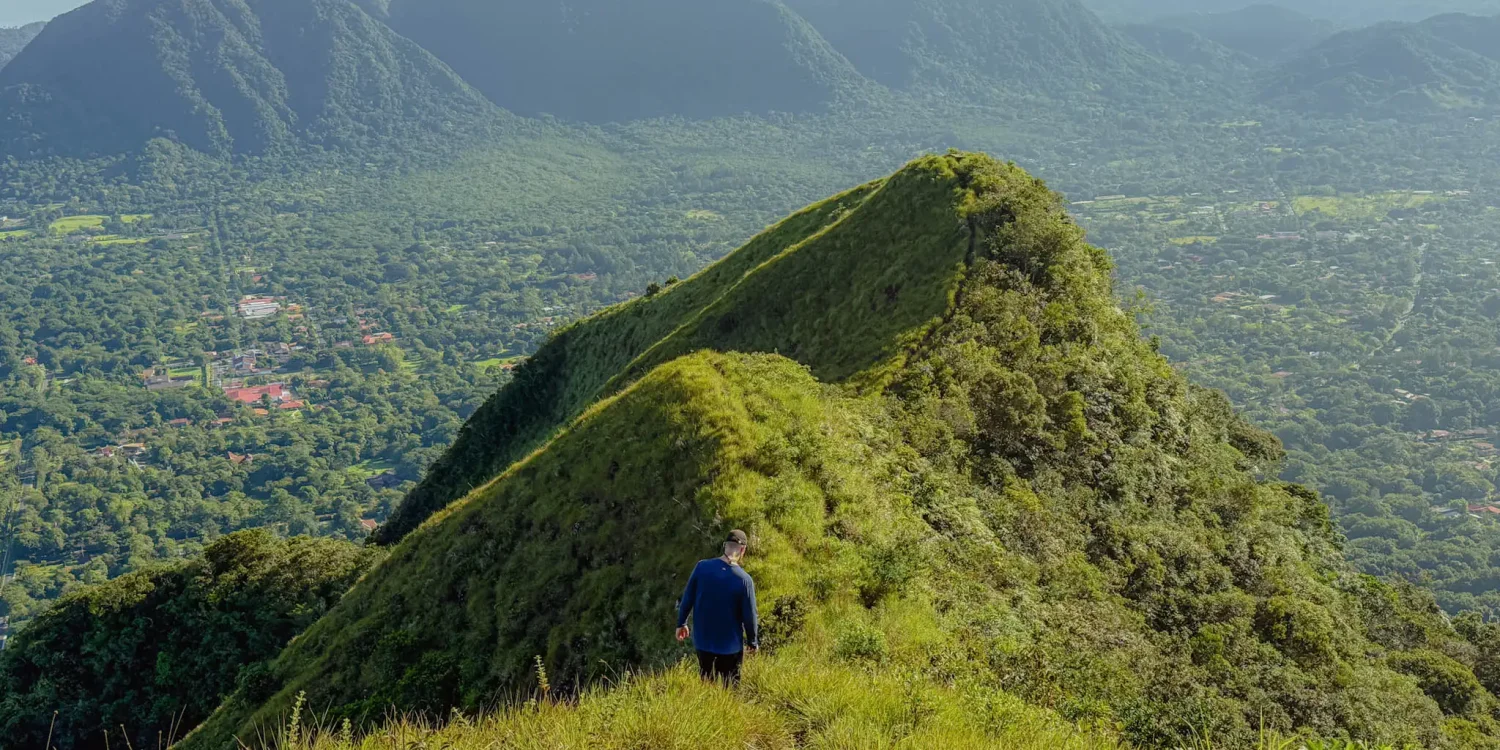 Hiker on the Cerro Cara Iguana trail above Valle de Anton with the crater valley and surrounding mountains visible below, Panama -- day trips from Panama City