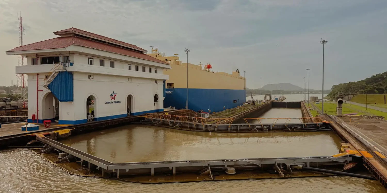 A large cargo ship passing through the Miraflores Locks on the Panama Canal with the Canal de Panamá control building in the foreground — Panama Canal things to do in Panama City
