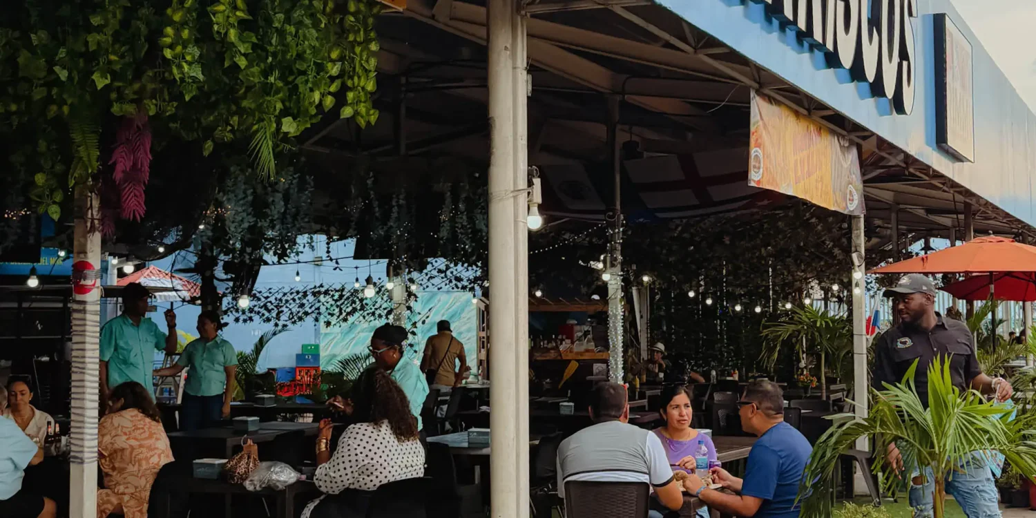 Diners eating at the outdoor seafood stalls at Mercado de Mariscos Panama City under string lights and hanging greenery — where to eat in Panama City