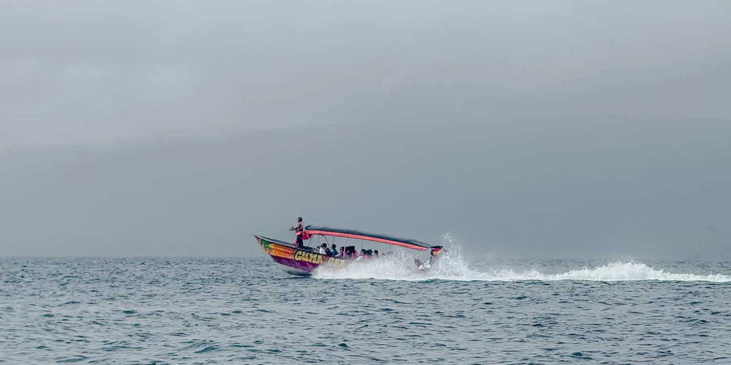 Colorful local water taxi speeding across choppy open water in San Blas under an overcast sky - best time to visit San Blas Islands Panama