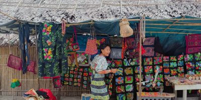 Guna woman in traditional dress arranging mola textiles at a market stall in San Blas - Guna Yala Panama responsible travel
