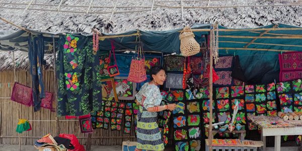 Guna woman in traditional dress arranging mola textiles at a market stall in San Blas - Guna Yala Panama responsible travel
