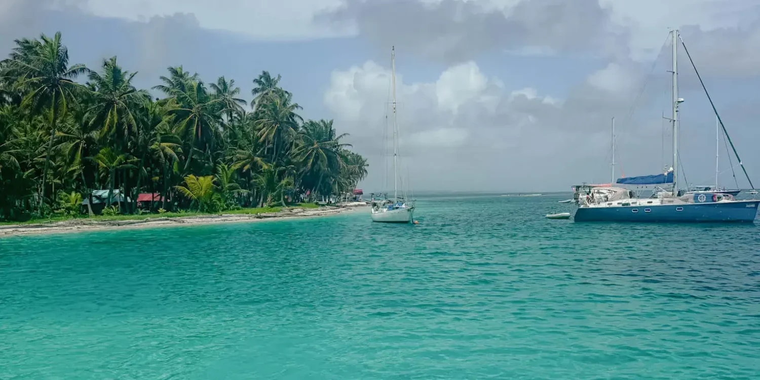 Turquoise water with sailboats anchored off a palm-covered island in San Blas - sailing San Blas Islands Guna Yala