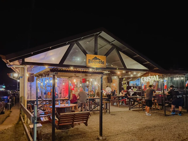 Lively outdoor seating area at Boquete Brewing Company lit up at night with string lights and guests dining -- Boquete Panama