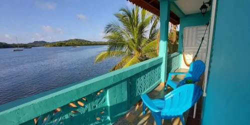 Teal balcony with blue chair and hammock at Casa Congo overlooking Portobelo bay with sailboats and palms -- Portobelo Panama