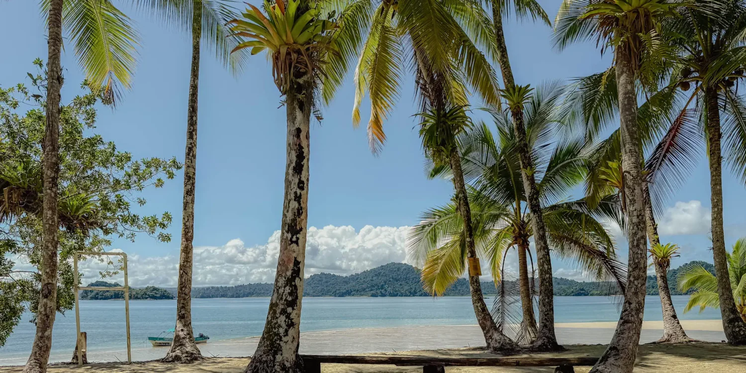 coiba-national-park-day-trip-boat-beach Palm fringed white sand beach and a small boat on a Coiba National Park day trip from Santa Catalina