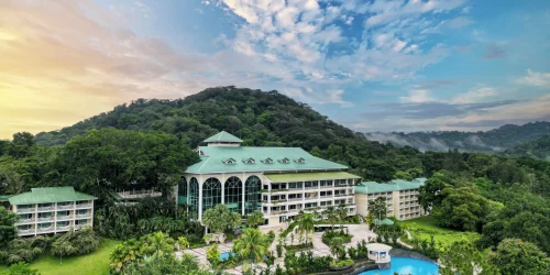 Aerial view of the Gamboa Rainforest Resort with its curved pool and rainforest hillside at golden hour -- Portobelo Panama