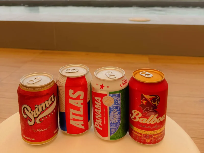Four cans of Panamanian beer including Prima, Atlas, Panama, and Balboa lined up on a table - Panama food guide