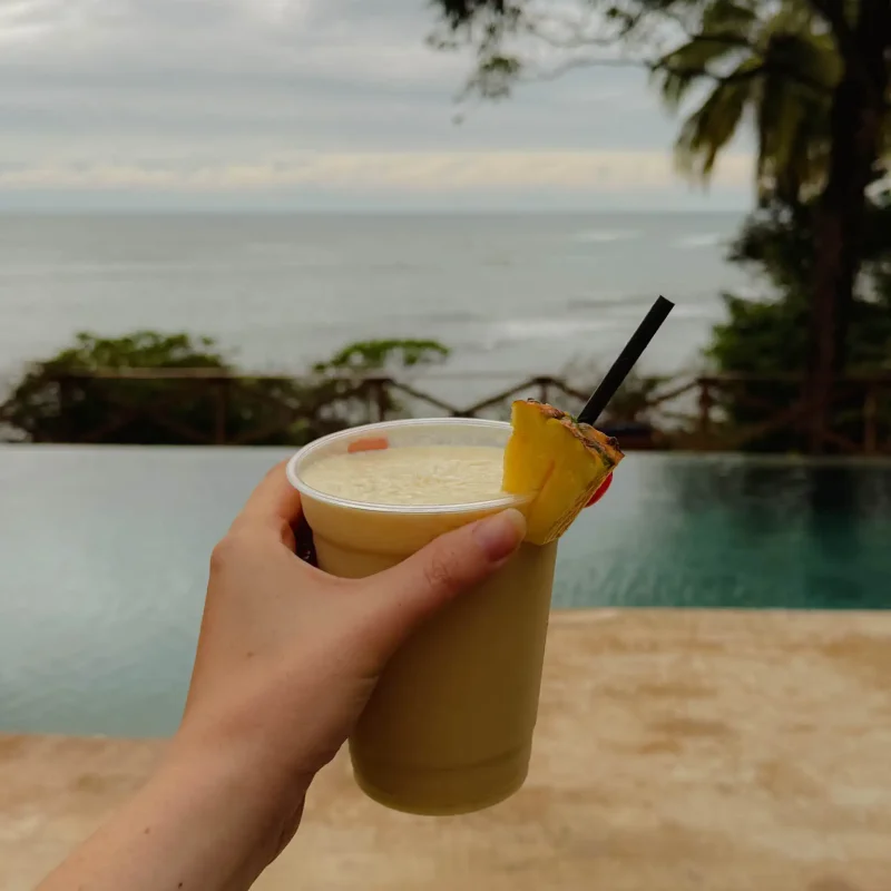 santa-catalina-poolside-drink-ocean-view Cold blended pineapple drink held above a pool with an ocean view in Santa Catalina, Panama