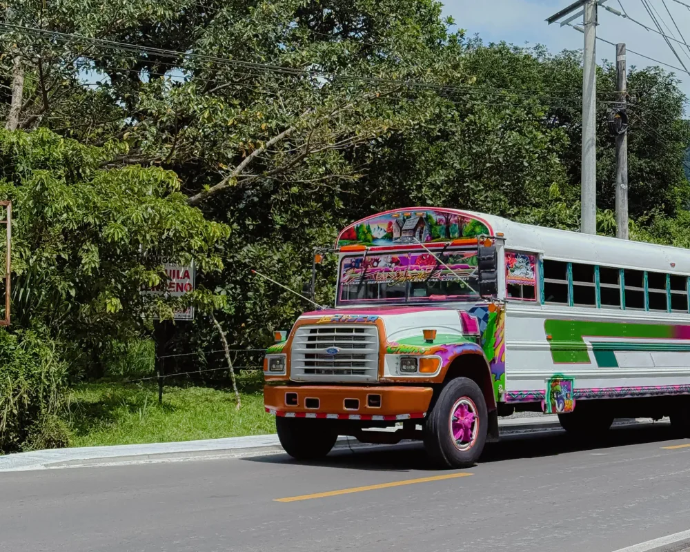 A brightly painted Panamanian diablo rojo bus on the road to Valle de Anton surrounded by tropical vegetation -- Valle de Anton Panama