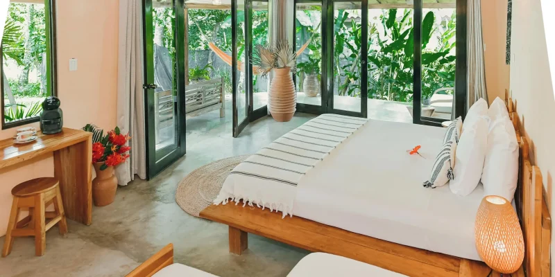 Boho style room with folding glass doors opening onto a tropical garden and hammock at Villa Coco in Santa Catalina, Panama